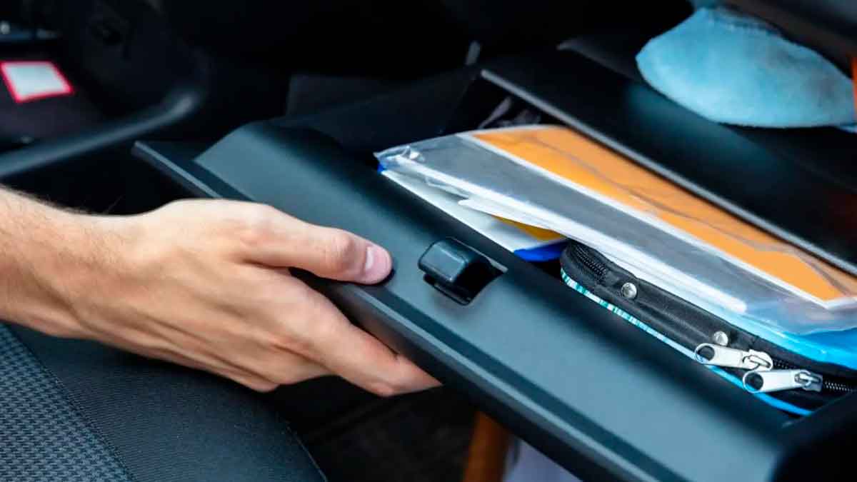 Mano abriendo la guantera de un coche con documentos y objetos revisados por la Guardia Civil durante controles de tráfico