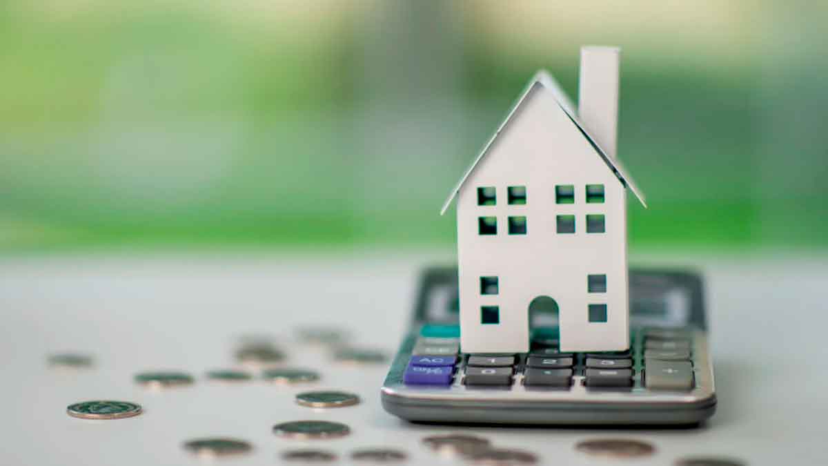 Casa sobre una calculadora con monedas, representando el encarecimiento de las hipotecas en España y Andalucía