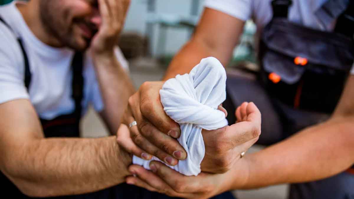 Trabajador con lesión en la mano recibiendo primeros auxilios tras un accidente laboral