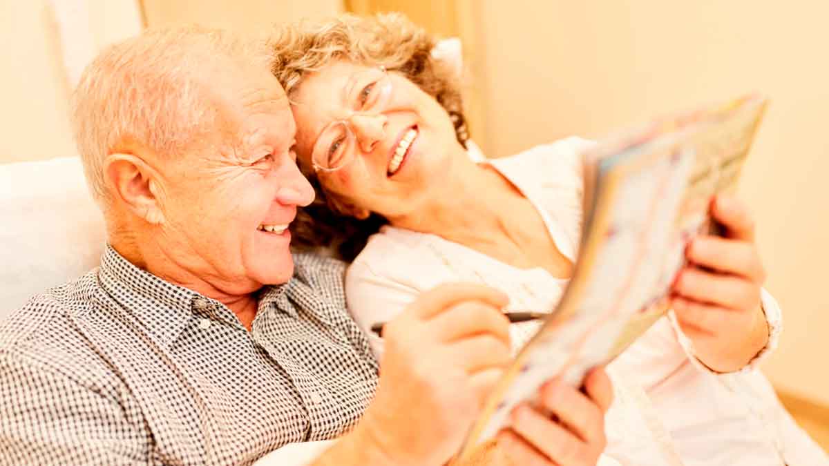 Pareja de jubilados sonrientes mientras revisan su paga de noviembre