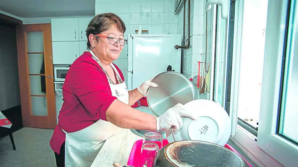 Trabajadora del hogar lavando platos en una cocina doméstica