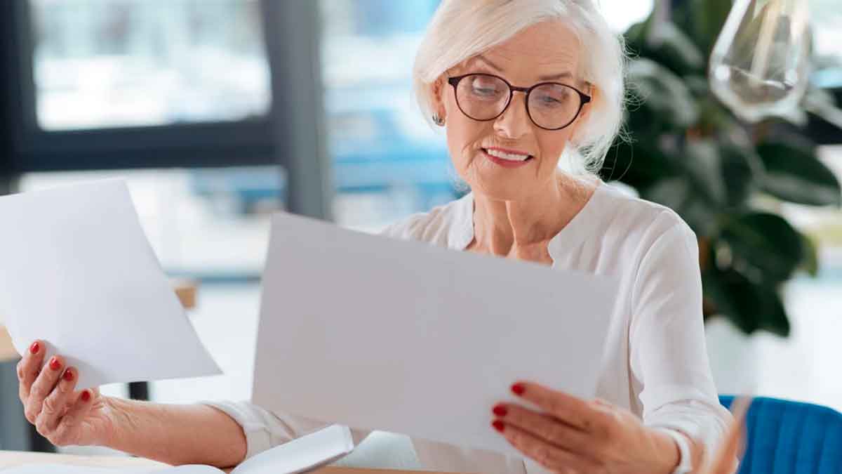 Mujer pensionista revisando documentos sobre el nuevo requisito del complemento por hijo de la Seguridad Social