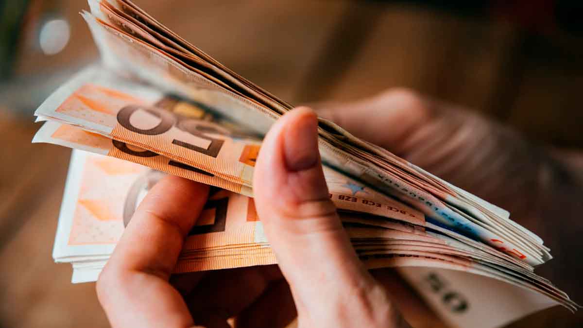 Persona contando billetes de euros relacionados con el pago único por nacimiento o adopción compatible con otras prestaciones