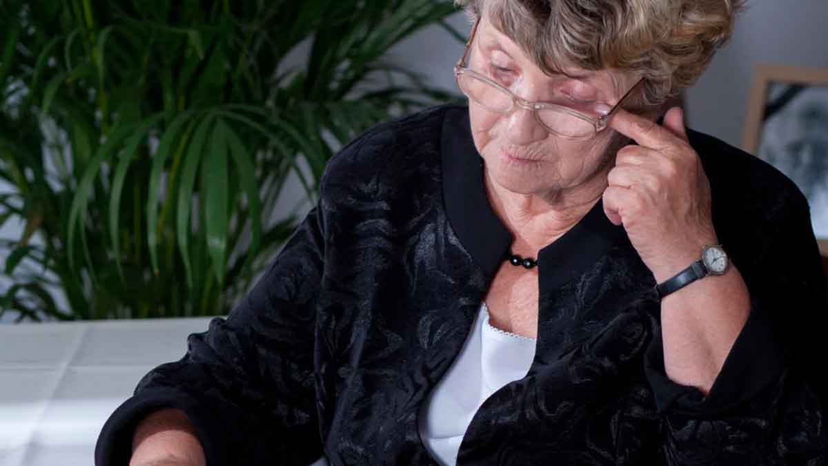 Mujer mayor revisando documentos sobre la pensión de viudedad