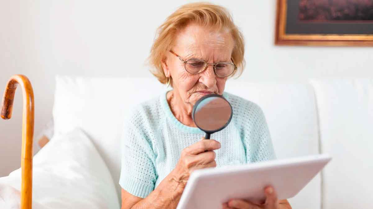 Persona mayor revisando un documento con una lupa en casa