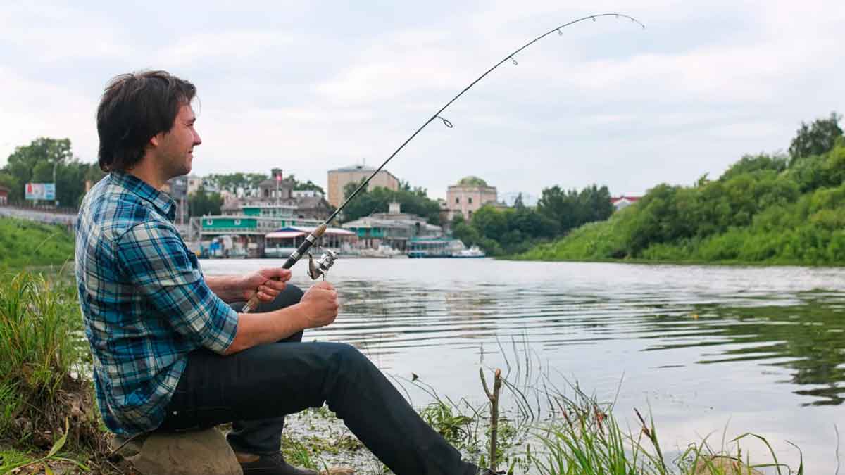 Hombre pescando en un río en Andalucía, información sobre licencias y multas por pescar sin permiso