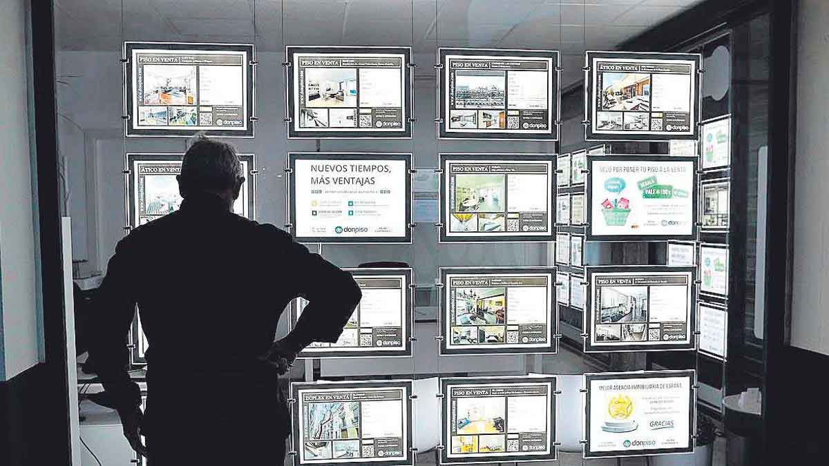 Hombre observando escaparate con anuncios de pisos en inmobiliaria en España