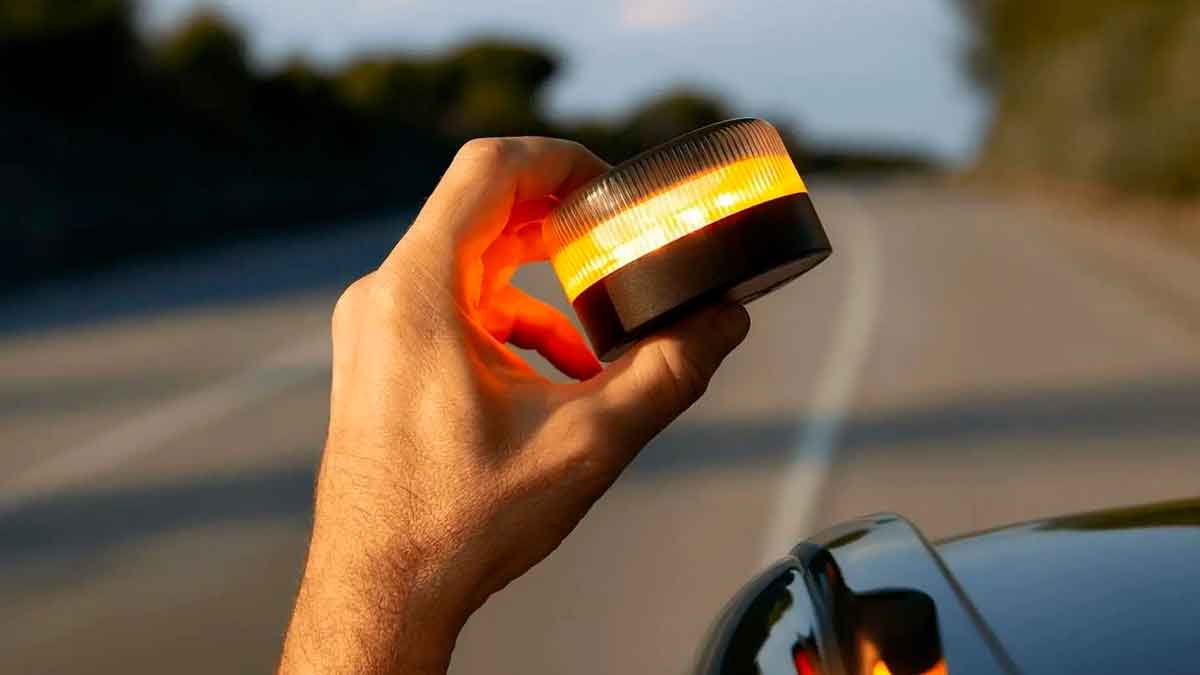 Persona comprobando una baliza V16 encendida junto a un coche sin enviar aviso a la DGT