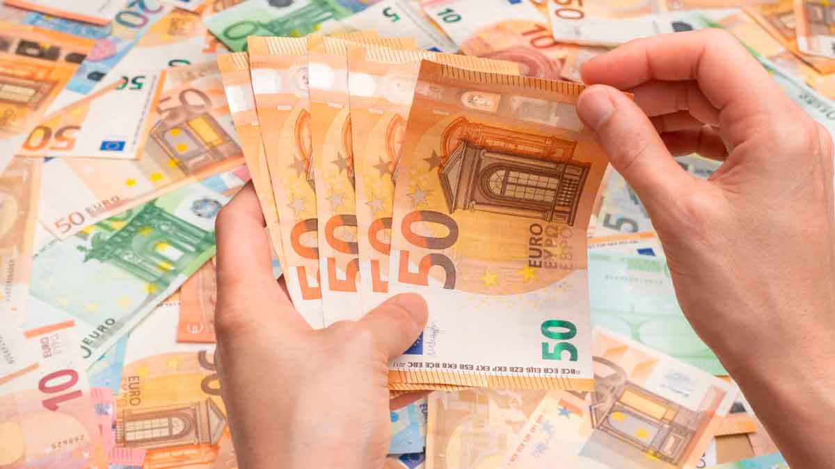 Manos contando billetes de 50 euros tras ganar un premio de la Lotería de Navidad
