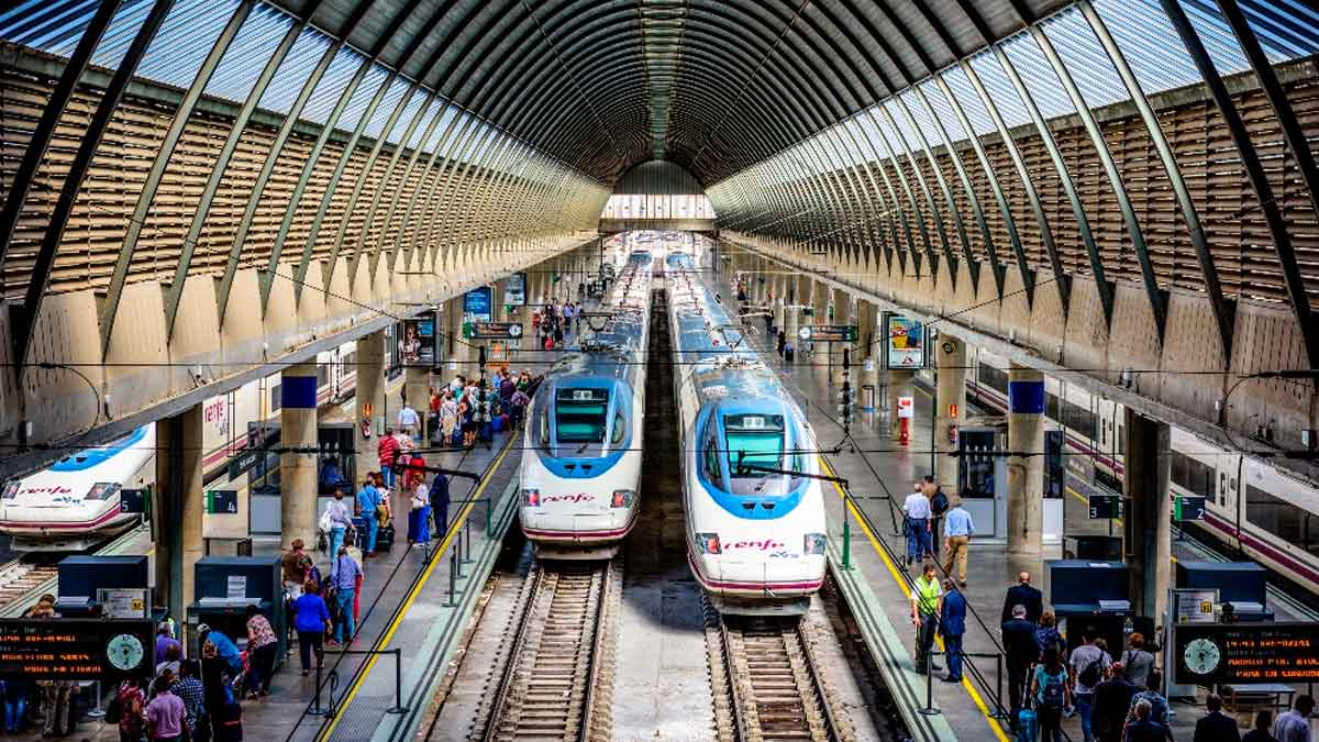 Trenes AVE de Renfe en andenes de una estación con viajeros esperando al embarque