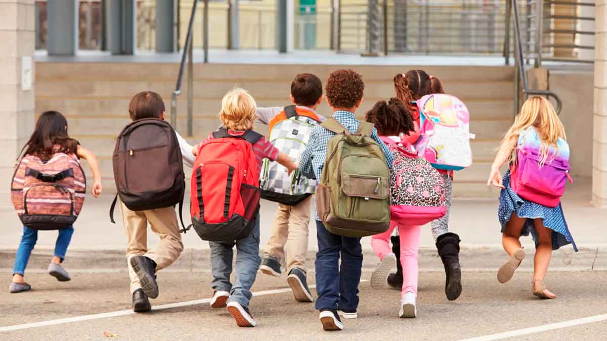 Niños entrando al colegio con mochilas, inicio de clases en centro educativo de Andalucía