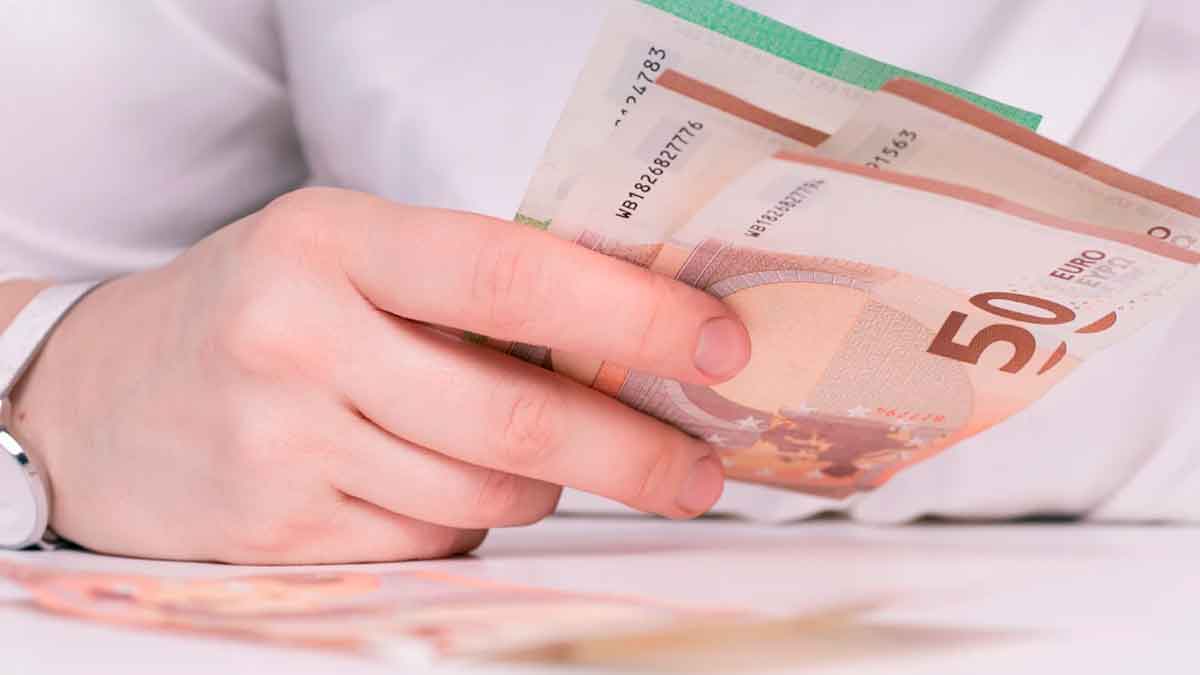 Persona contando billetes de 50 euros representando el salario más común en España y su cercanía al SMI