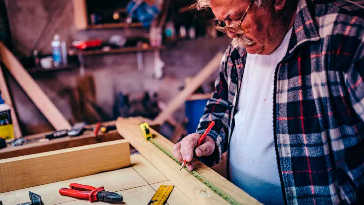 Persona mayor realizando un trabajo de carpintería en su taller como actividad autónoma puntual