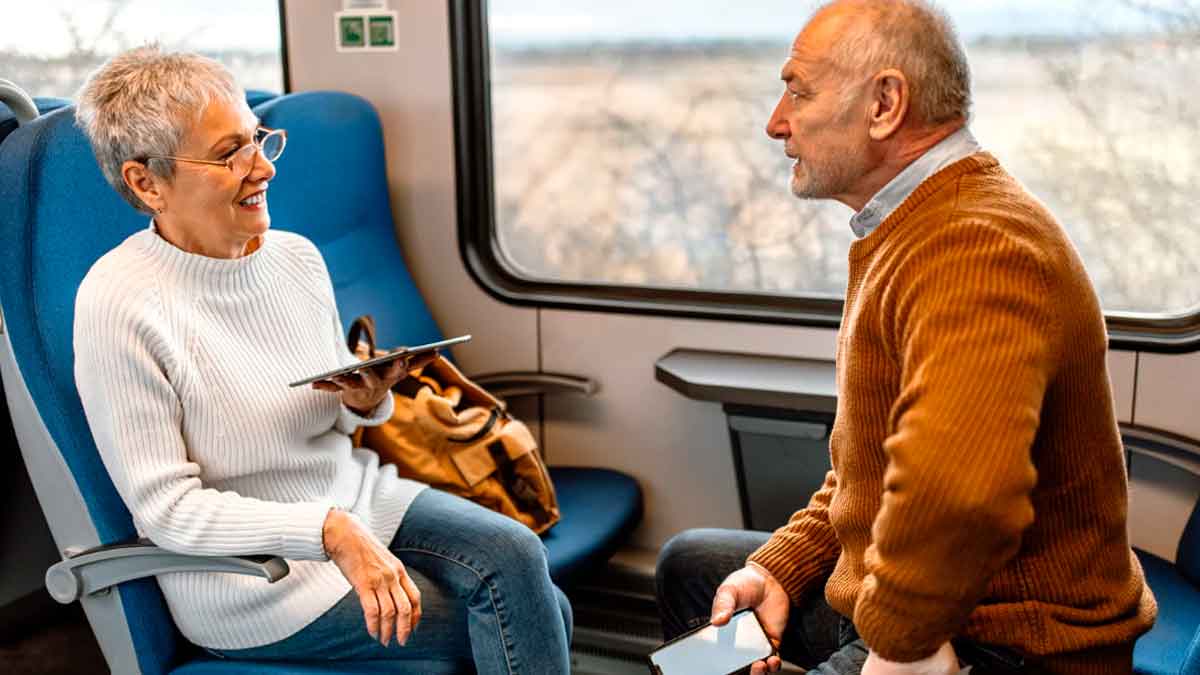 Pareja mayor viajando en tren con la Tarjeta Dorada de Renfe y disfrutando de descuentos del 40 por ciento