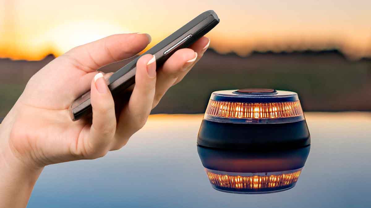 Persona usando el móvil junto a una baliza V16 encendida al atardecer