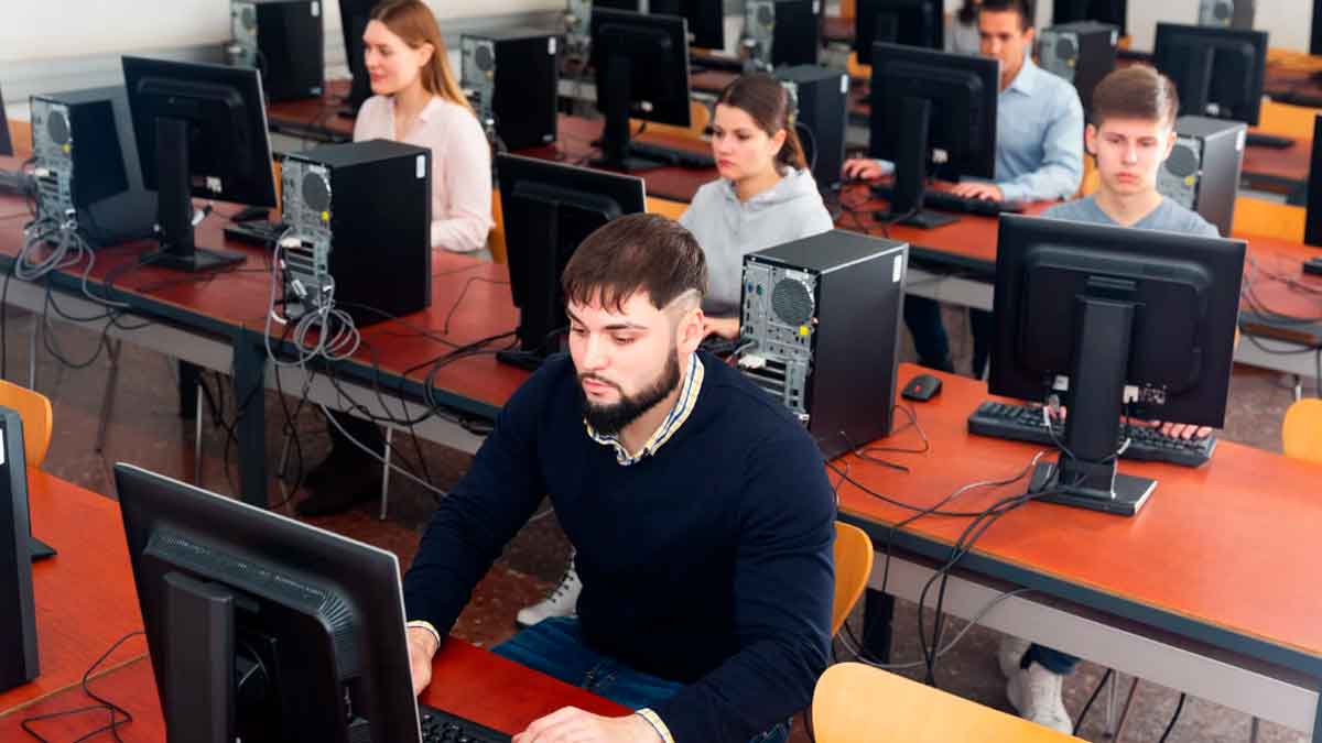 Estudiantes realizando prácticas formativas en un aula de informática relacionadas con la nueva ley del salario mínimo en prácticas