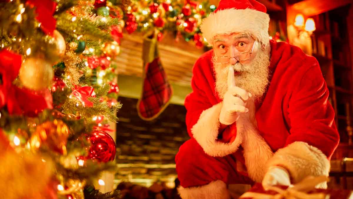 Papá Noel junto al árbol de Navidad y los regalos, símbolo del origen de la tradición navideña