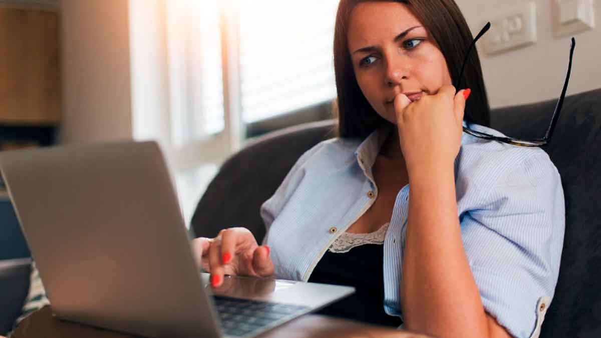 Mujer trabajando con un portátil en casa mientras revisa información sobre teletrabajo y conciliación laboral