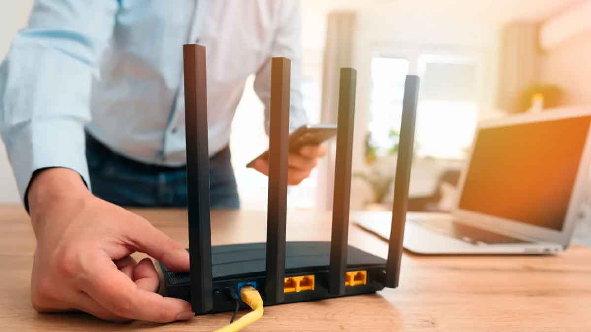 Router de internet en una vivienda mientras un usuario revisa cambios en su conexión de móvil e internet