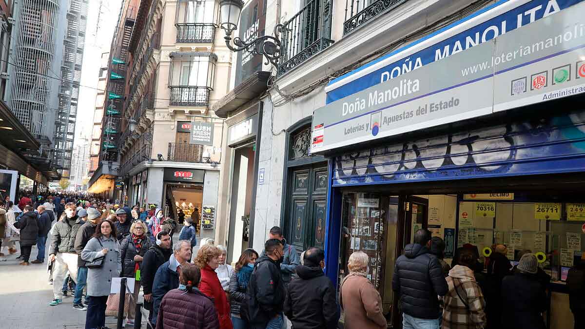 Cola de personas frente a la administración de lotería Doña Manolita en Madrid para comprar décimos de Navidad