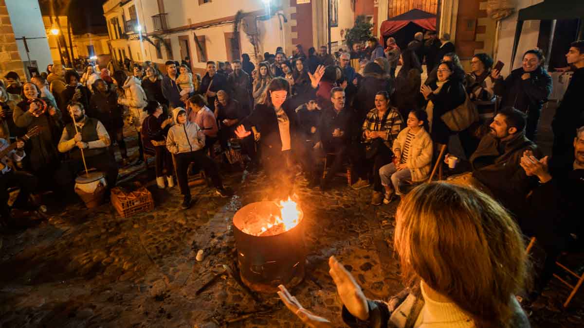 Celebración navideña andaluza en la calle con música tradicional, fuego y vecinos reunidos cantando villancicos