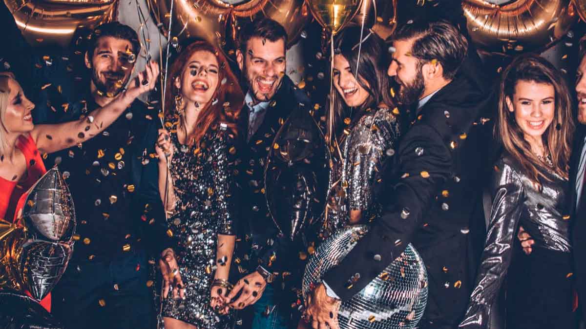 Personas celebrando una fiesta de Nochevieja con confeti y globos en un local nocturno