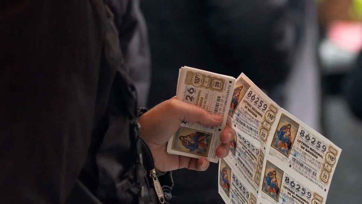 Persona sosteniendo varios décimos de Lotería de Navidad compartidos para reclamar el premio según el Código Civil