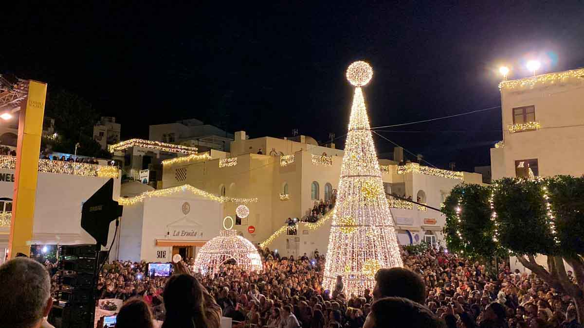 Multitud en un pueblo andaluz iluminado con un gran árbol de navidad y decoraciones festivas durante las celebraciones navideñas