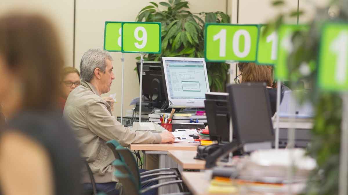 Oficina de la Seguridad Social con trabajadores atendiendo trámites relacionados con bajas médicas y cotizaciones
