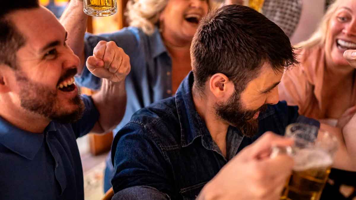Grupo de amigos celebrando la tardebuena en un bar, brindando con cervezas durante la Navidad