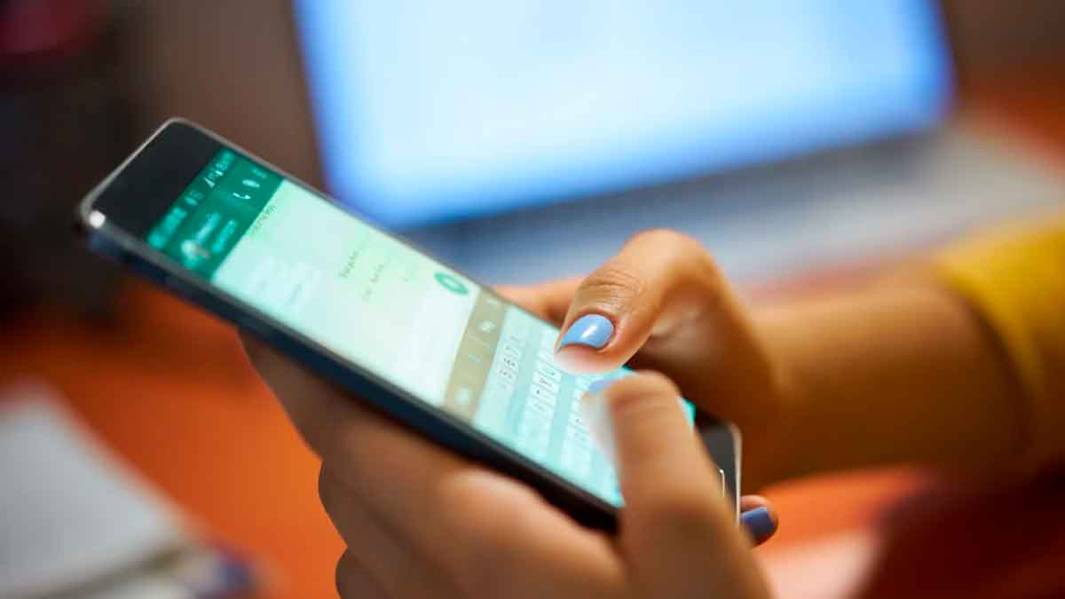 Persona usando un teléfono móvil mientras escribe un mensaje en WhatsApp