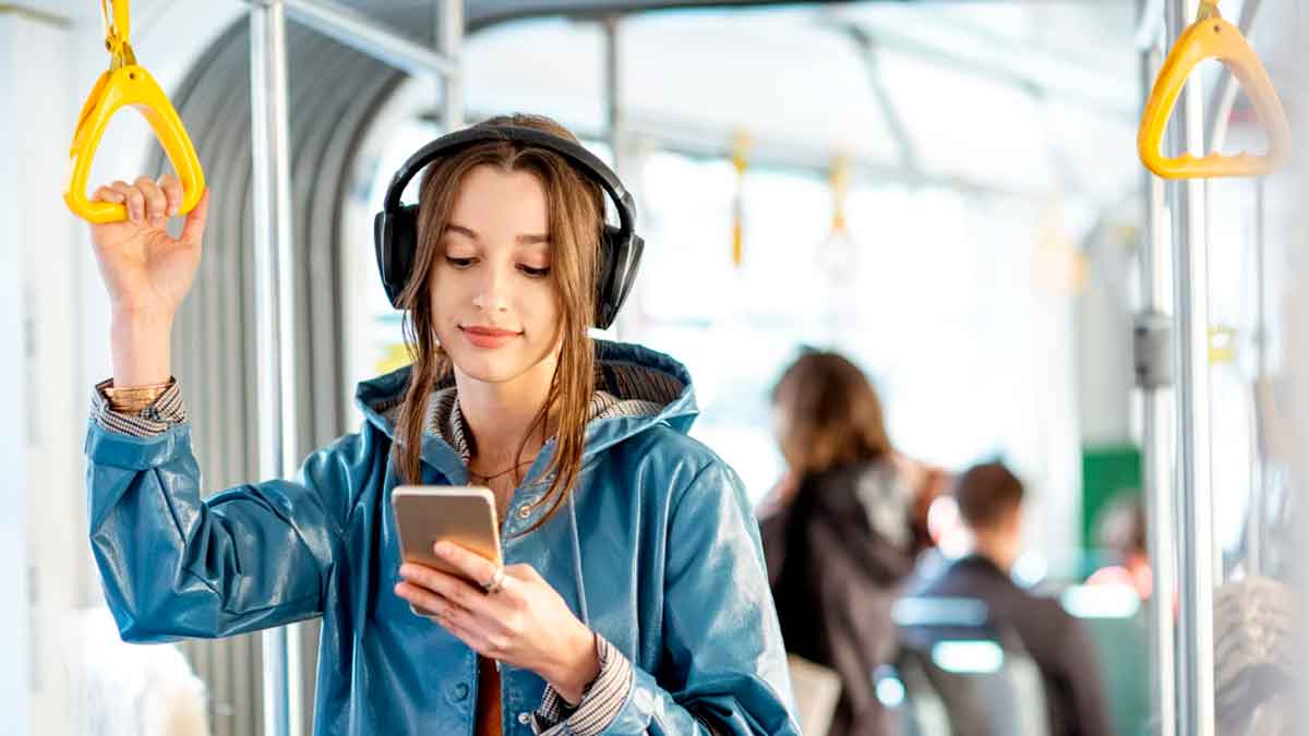 Joven usuaria consultando el móvil mientras viaja en transporte público en Andalucía