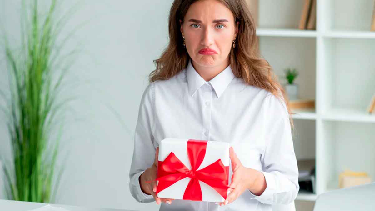Mujer sostiene un regalo envuelto tras Reyes reflejando decepción por un obsequio no deseado