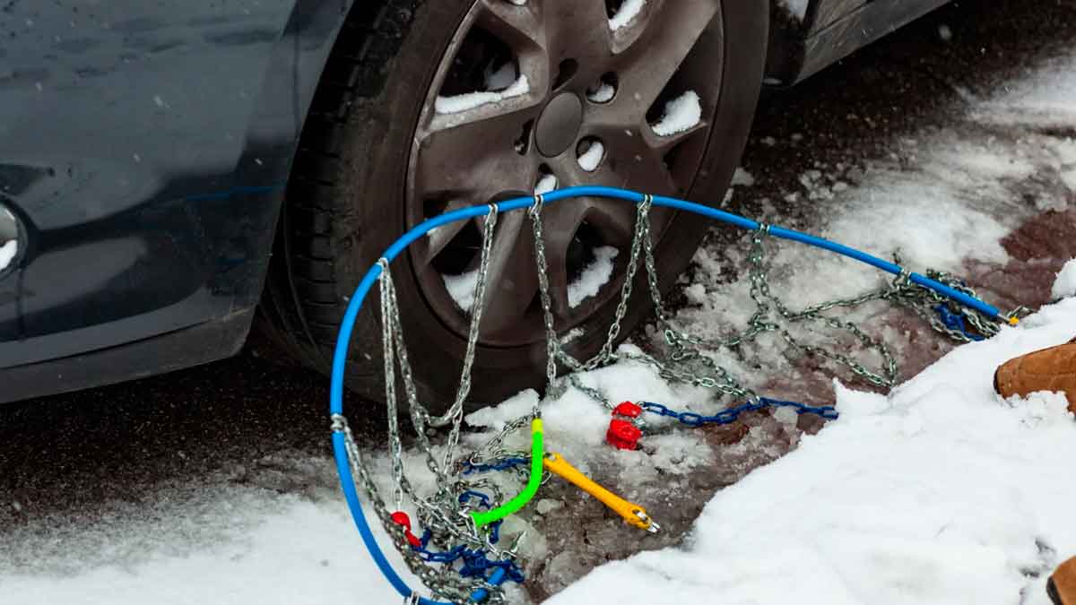 Cadenas de nieve mal colocadas en la rueda de un coche sobre carretera nevada