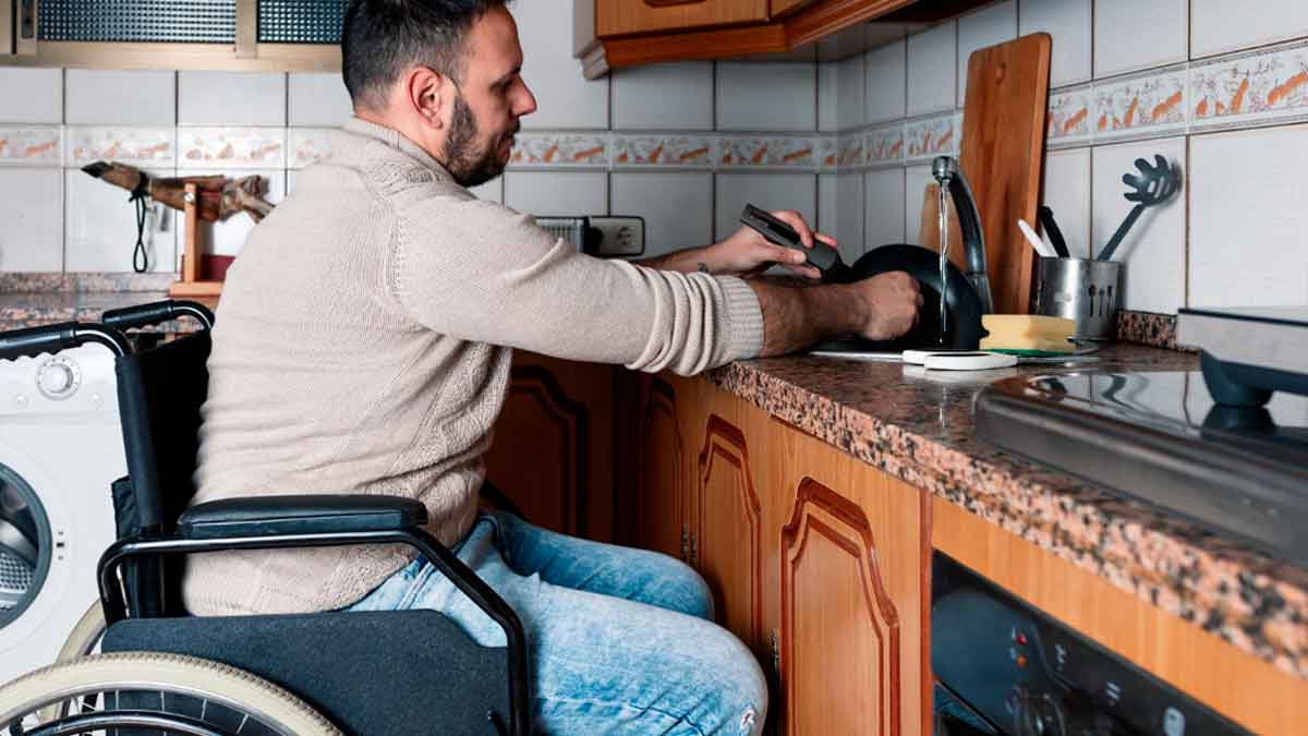 Persona con discapacidad en silla de ruedas realizando tareas domésticas en su vivienda