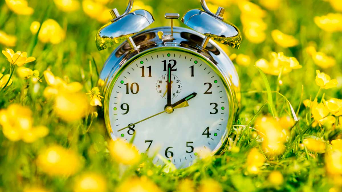 Despertador analógico sobre césped en primavera por el cambio de hora en España 2026