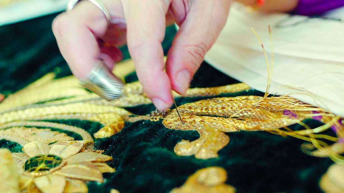 Bordado artesanal en oro de una pieza de arte sacro durante un proceso de formación profesional