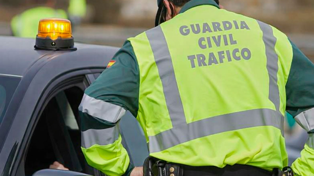 Guardia Civil de Tráfico junto a un coche con baliza V16 encendida en el techo durante un control en carretera