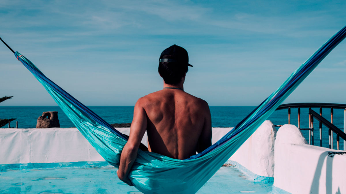 Hombre descansando en una hamaca frente al mar durante sus vacaciones