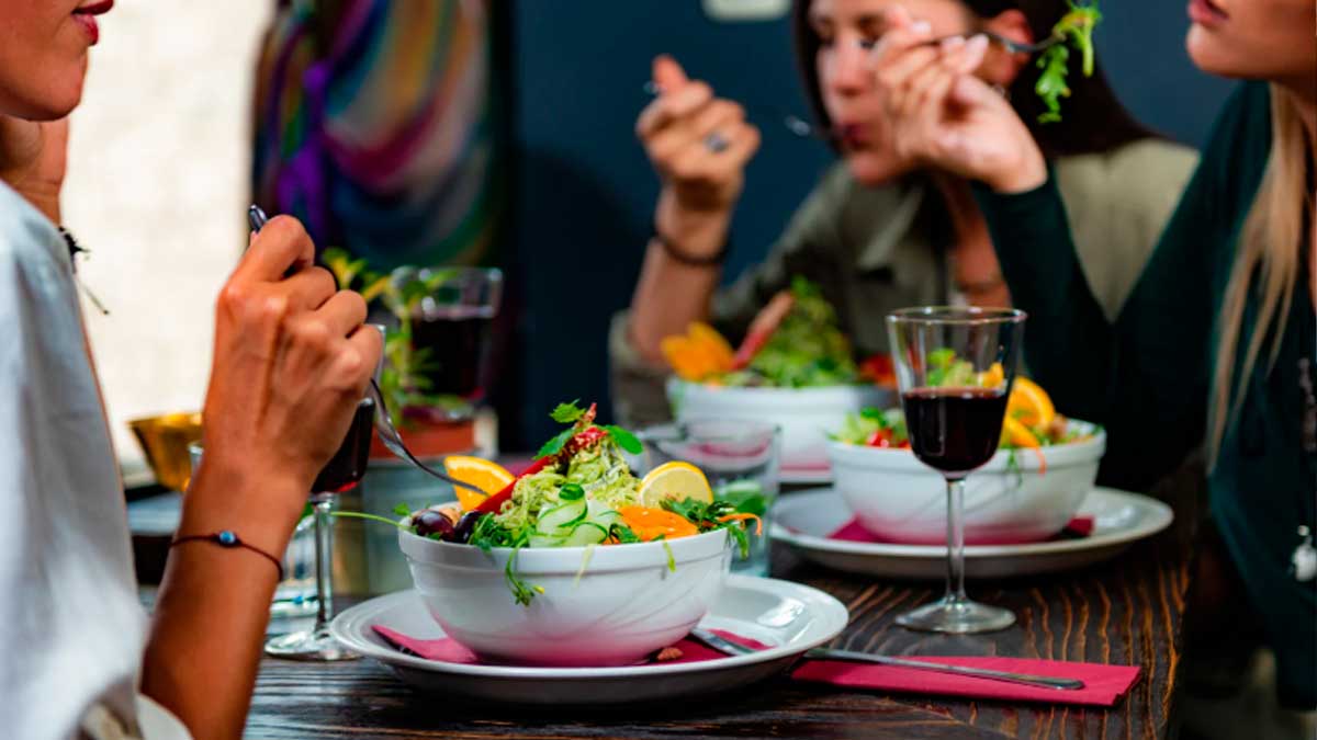 Personas comiendo ensalada de verduras de hoja verde siguiendo dieta MIND saludable