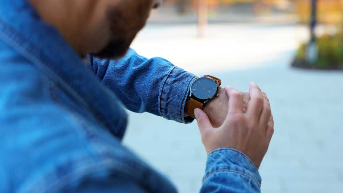 Trabajador mirando el reloj tras llegar tarde al trabajo en un caso de despido declarado improcedente por la Justicia
