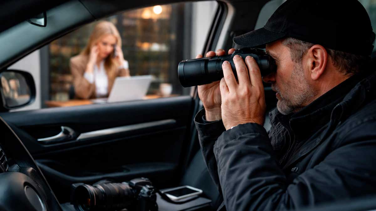 Detective vigilando a trabajadora desde un coche en un caso de control laboral