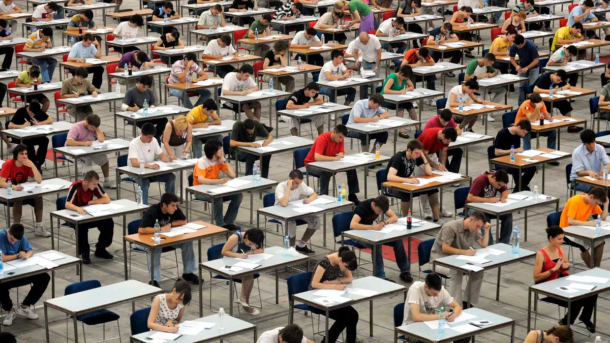 Aspirantes realizando examen de oposiciones en aula multitudinaria para acceder a empleo público en España