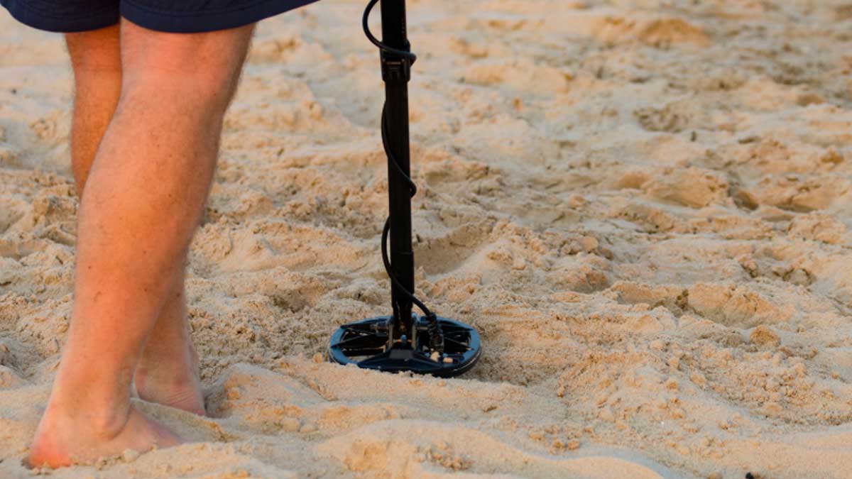 Persona usando detector de metales en la arena de una playa andaluza