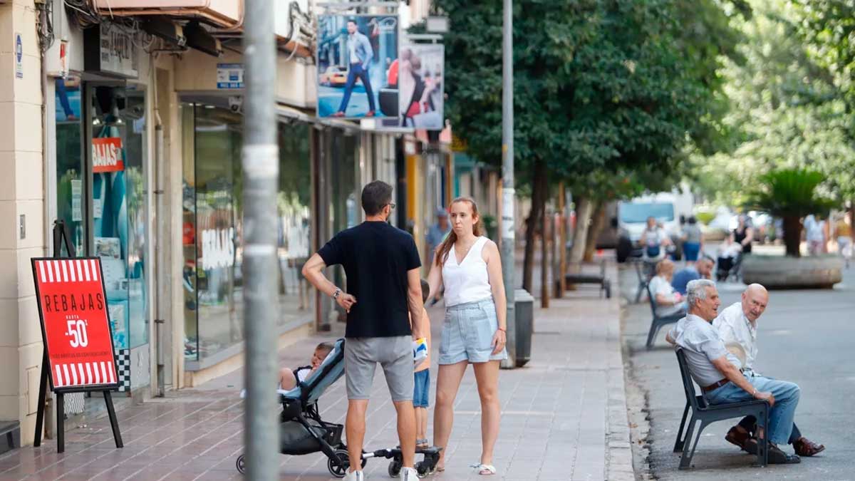 Personas paseando y sentadas en la calle Viñuela tras la peatonalización en barrios de Córdoba