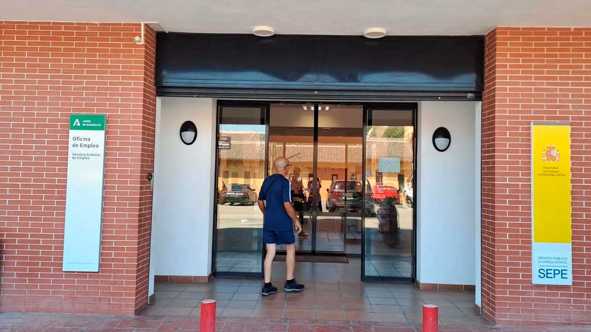 Trabajador con una maleta frente a una oficina del SEPE tras regresar del extranjero.